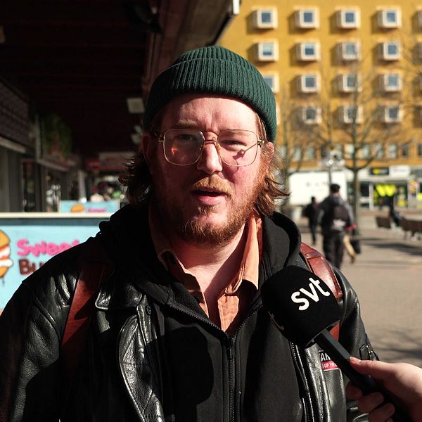 SVT intervjuar person på gata, orange byggnad i bakgrunden.