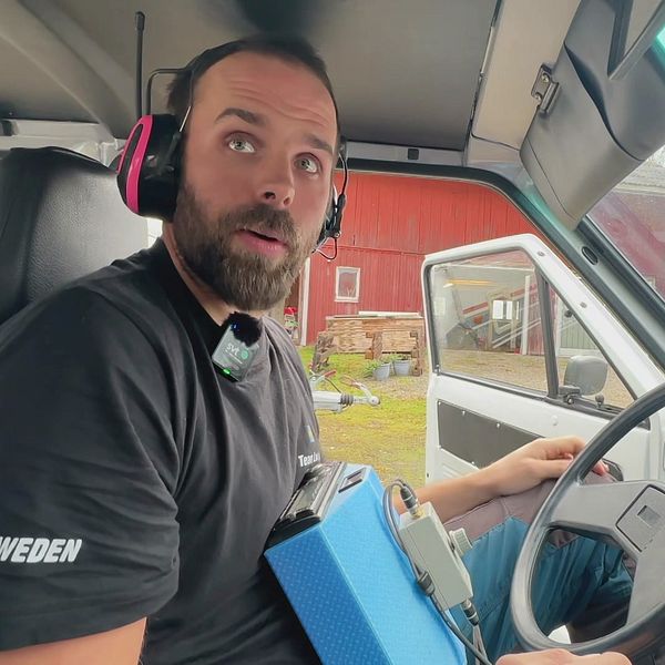 Fredrik Nymans sitter i bilens förarsäte med hörselkåpor och mäter billjudsnivå.
