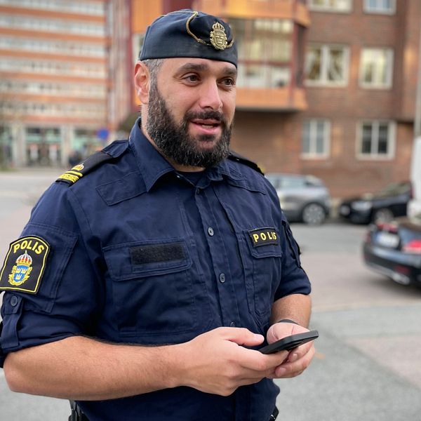 Yttre befälet Joseph Antabi från polisen håller i en mobiltelefon utomhus.