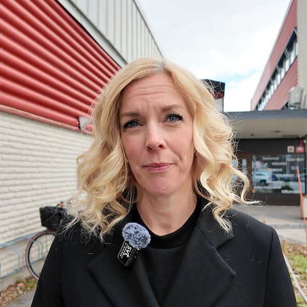 Person står utanför SVT:s byggnad, mikrofon synlig på rockslaget.