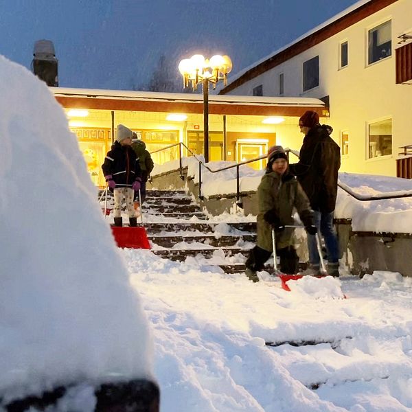 Fler barn iklädda vinterkläder skottar snö