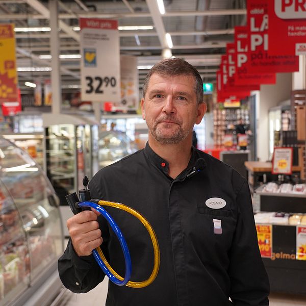 ICA-handlaren står med två lås och tittar in i kameran.