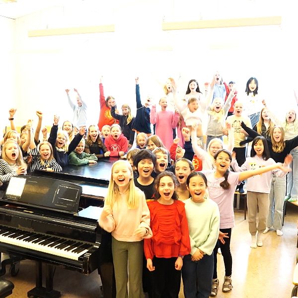 Glada barn som jublar framför kameran efter en musiklektion.