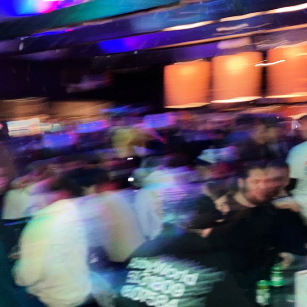 En bild från en afterski i Åre. Stökig miljö där med suddiga människor som sitter uppradade vid bord och dricker alkohol.