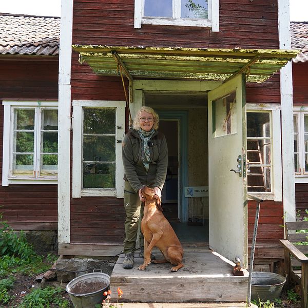 Nya husägaren Karin utanför huset tillsammans med sin hund.