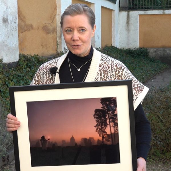 Kvinna håller inramat foto i händerna.
