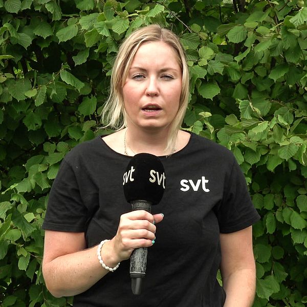 SVT:s reporter Beatrice Emmerik står med en mikrofon i handen framför en buske.