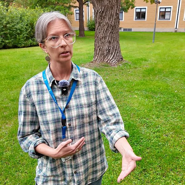 Vilthandläggaren Ellinor Sahlén gestikulerar utomhus i grönskande miljö.