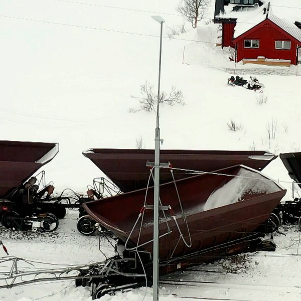 urspårade malmvagnar i vintermiljö, en röd stuga i bakgrunden