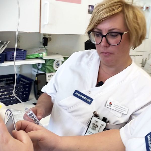 Två kvinnliga sjuksköterskor programmerar en droppställning.