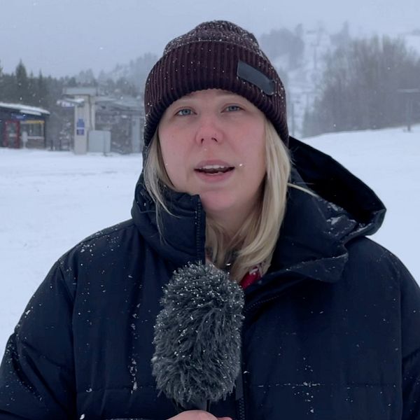 En kvinna med blont hår och svart mössa håller i en mikrofon