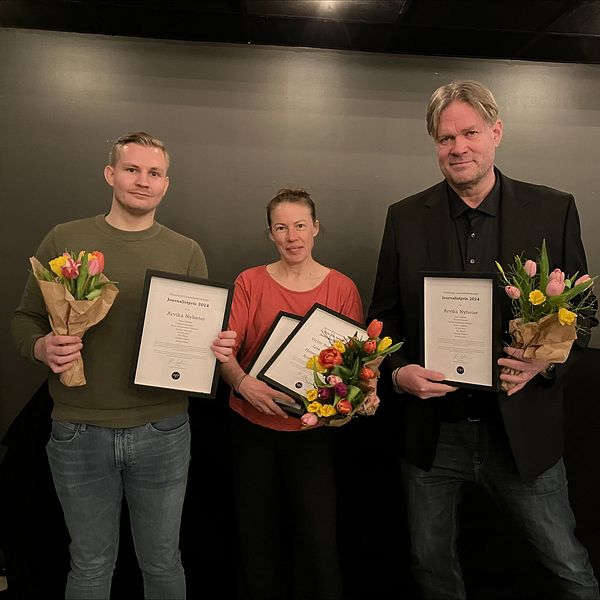 Tre personer håller diplom och blombuketter, stående bredvid varandra.