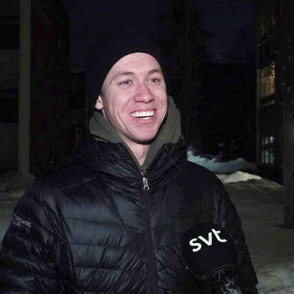 Emil Persson, skidåkare står och ler i en svart dunjacka i ett bostadsområde.