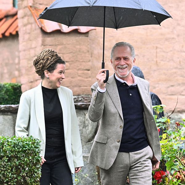 Amanda Lind och Daniel Helldén under ett samtal med paraply utomhus.