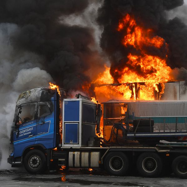 En brandman sprutar vatten på en brinnande lastbil.