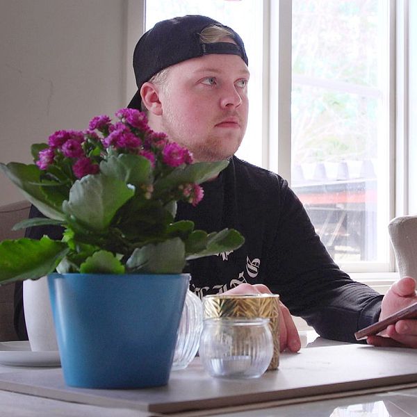 Anton Svedberg sitter vid köksbordet i Östersund och scrollar i mobilen