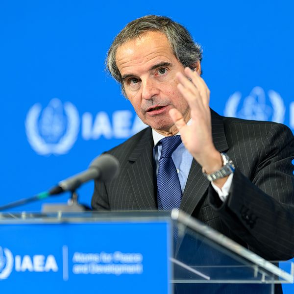 Person talar vid IAEA:s talarstol framför blå bakgrund med IAEA-logotyp.