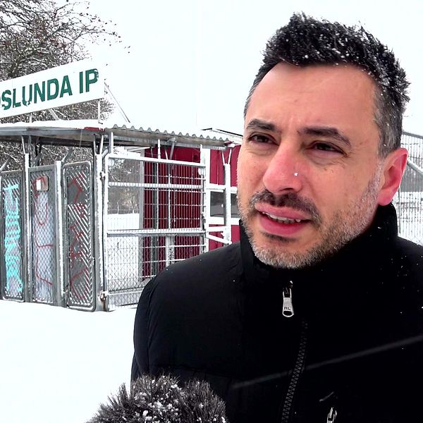 Fredrik Krait står framför Fröslunda IP i snöigt väder, med en fotbollsstadion och byggnad i bakgrunden.