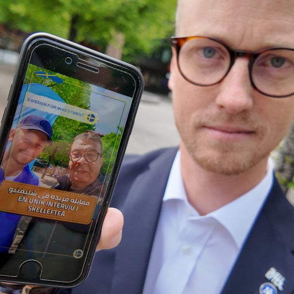 Moderaten Andreas Löwenhöök håller upp en mobiltelefon och visar bild från ett videoklipp