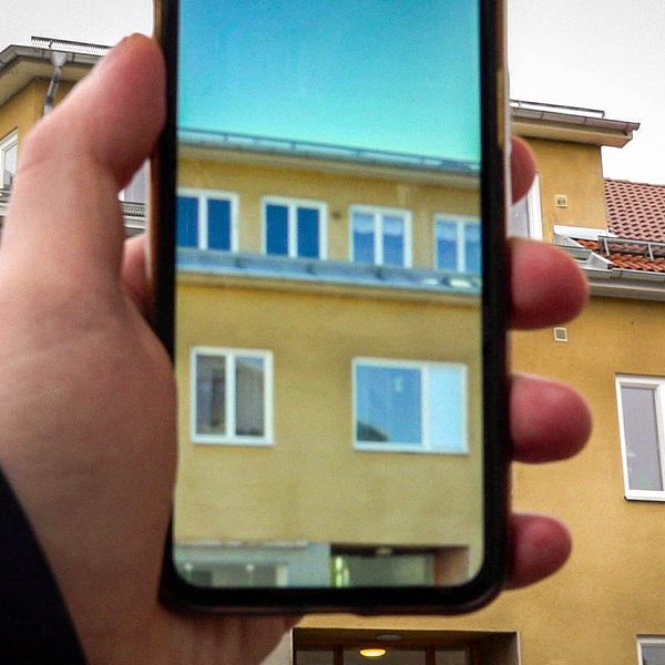 En telefon med en bild som visar hur huset såg ut före fönsterbytet i Nyköping.