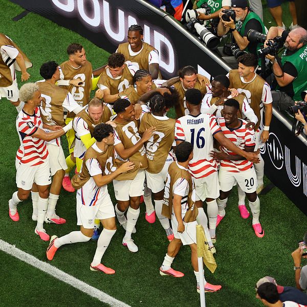 Spelare firar mål vid sidlinjen under USA:s premiäruppvisning