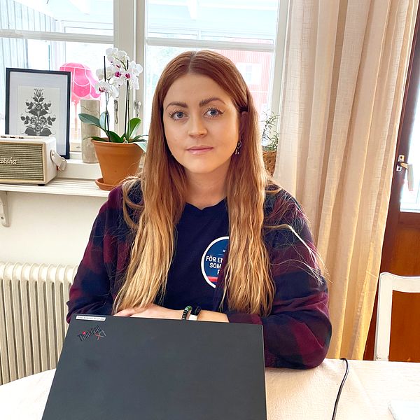 en politiker vid ett köksbord och en laptop framför henne på bordet