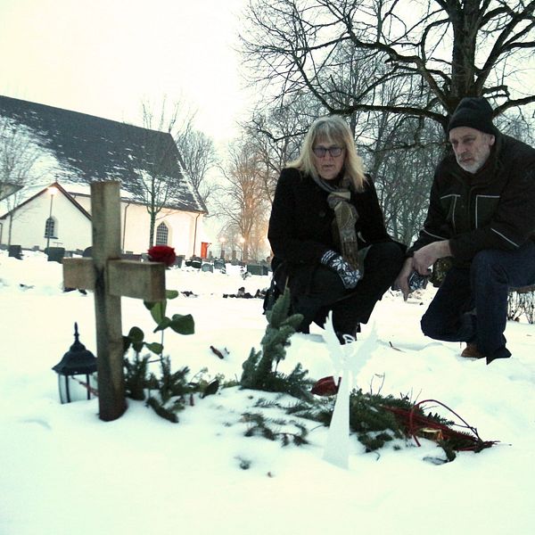 två personer sitter vid grav