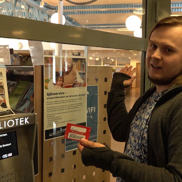 En bibliotekarie visar upp hur man kan komma in i ett bibliotek på Andersberg, Gävle med hjälp av självservice.