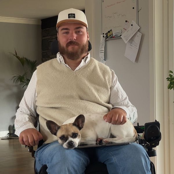 Jonathan Erikson Torell sitter i sin rullstol med en hund i knäet