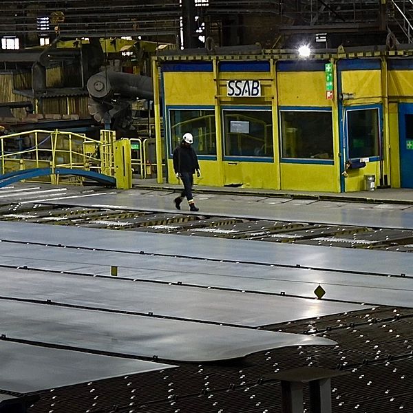En man med vit hjälm går i en av SSAB:s industrilokaler i Oxelösund.