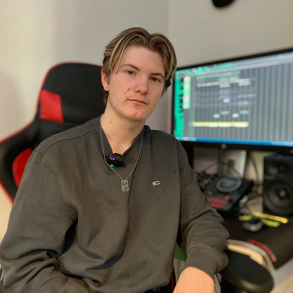 Person i inspelningsstudio med dator och ljudutrustning i bakgrunden.