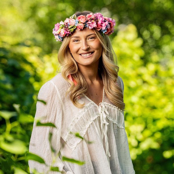 Ebba Årsjö med blomsterkrans i grönskande sommarporträtt