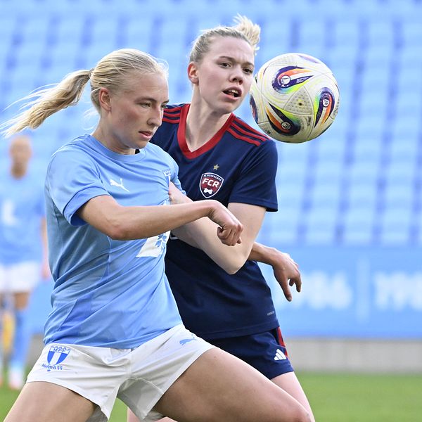 Två fotbollsspelare tävlar om bollen på plan.