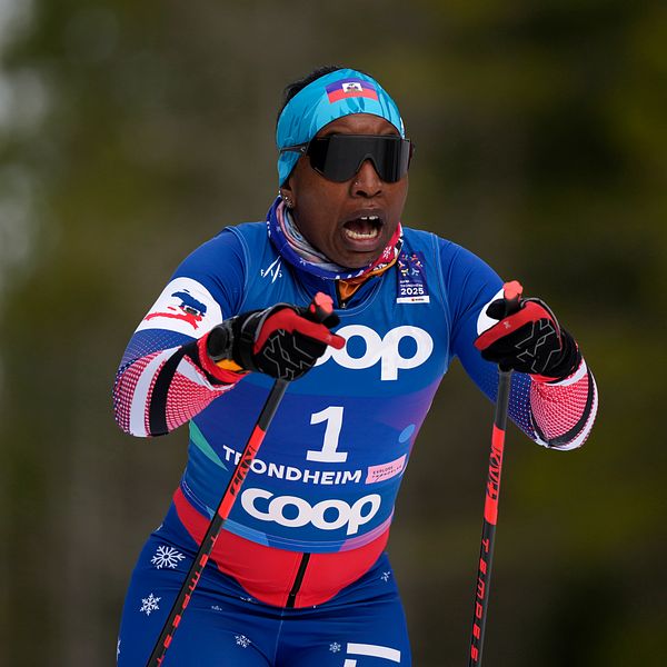Skidåkare i blå tävlingsdräkt från COOP i full fart i skidtävling.