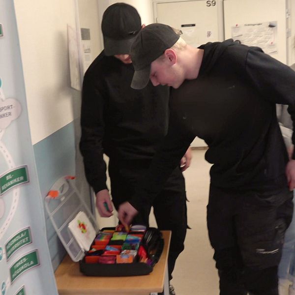 två tonårskillar plockar kondomer från en låda i en korridor