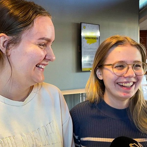Två tjejer i 20-årsåldern står i en korridor på Karlstads universitet och skrattar.