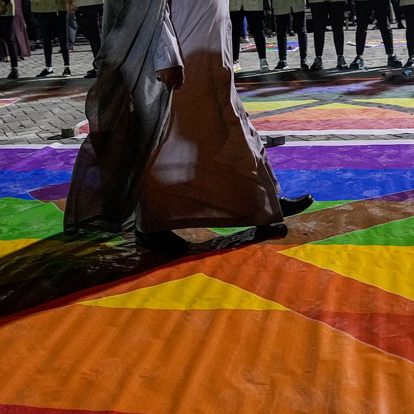 Människor kliver över en regnbågsflagga