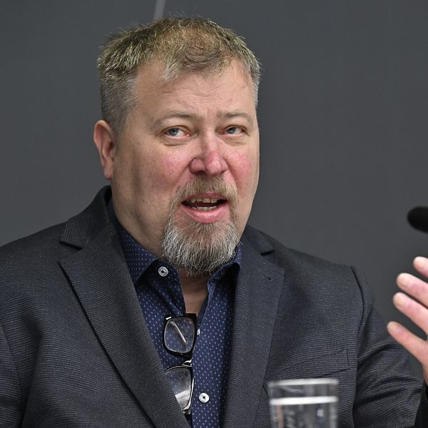 Professorn i förvaltningsrätt Olle Lundin på en presskonferens med en mikrofon framför sig.