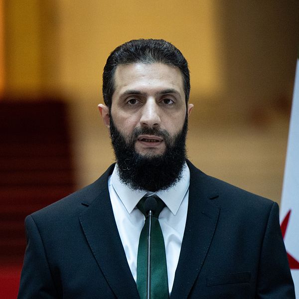 Syriens nya ledare AZhmad Al-Sharaa i mörk kostym och vit skjorta vid en pressträff i Damaskus.