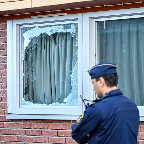 Politiet og en fasade med knust vindu