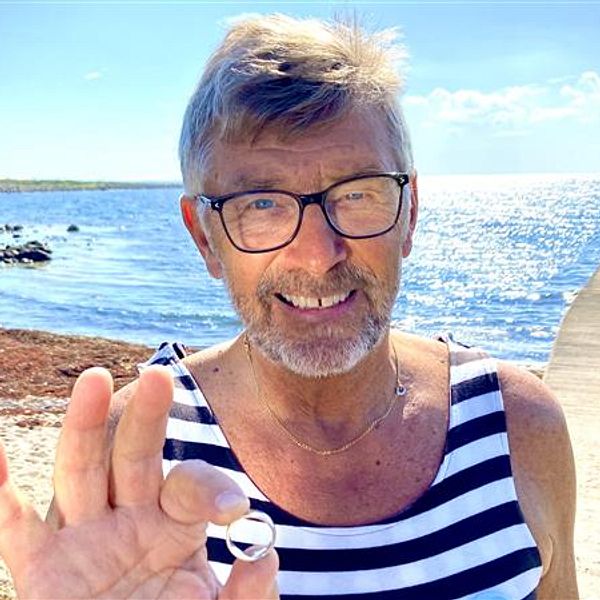 Stefan Bengtsson visar upp vigselringen han hittade vid stranden i Mölle. I bakgrunden badbryggan vid Fågelviken.