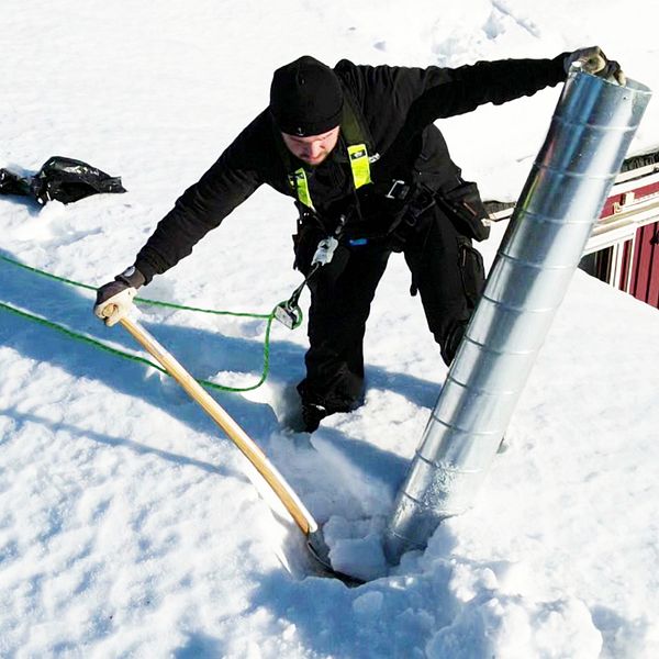 En person som mäter snö på taket