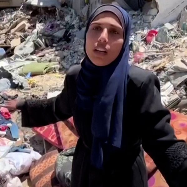 En palestinsk kvinna som står mitt i rasmassor av hus.