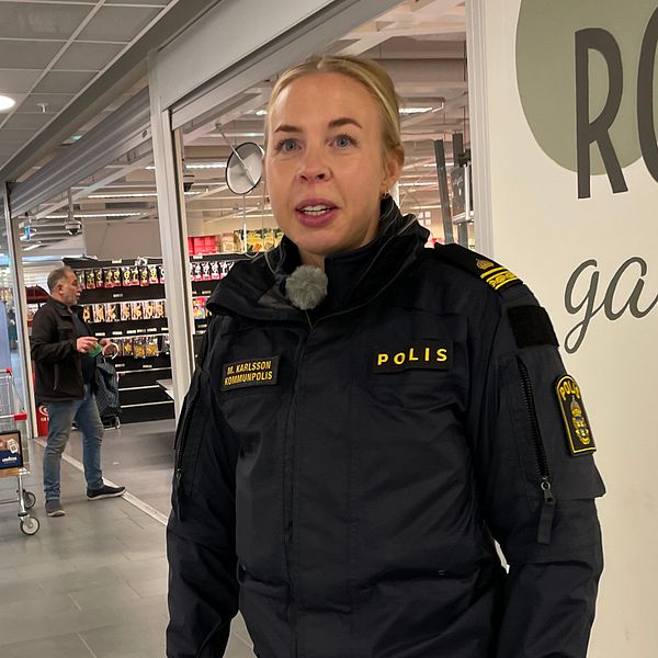En kvinnlig polis står i ett köpcenter