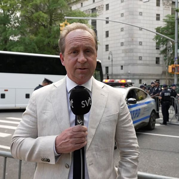En reporter utomhus med mikrofon i handen.