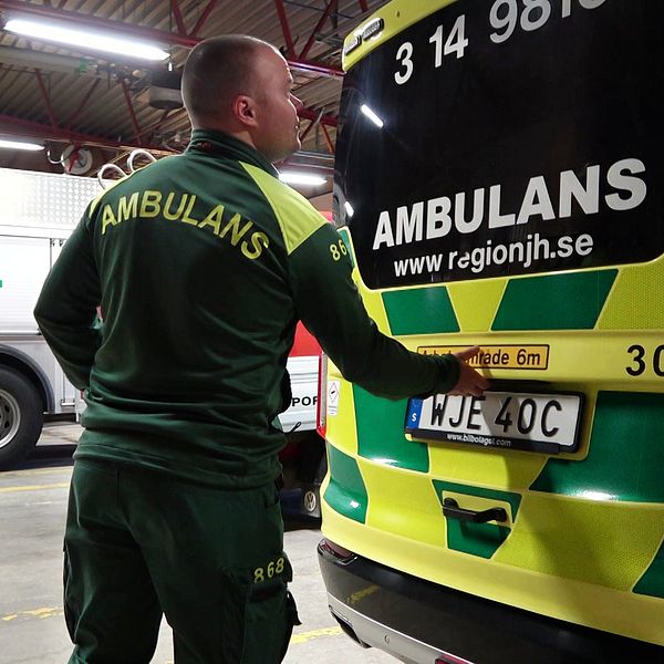 En ambulanssjuksköterska är på väg att öppna bakluckan till en av region Jämtland Härjedalens ambulansbilar i ett garage.