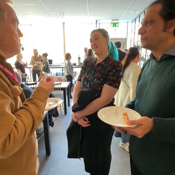En grupp människor samtalar i en livlig kafémiljö.