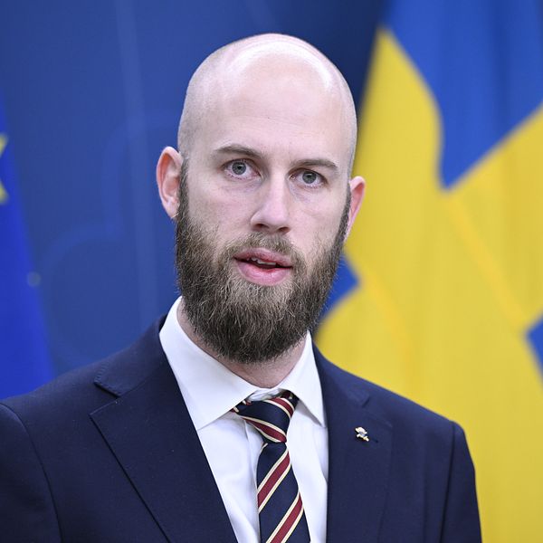 Carl-Oskar Bohlin (M) framför en Sverigeflagga på en pressträff.