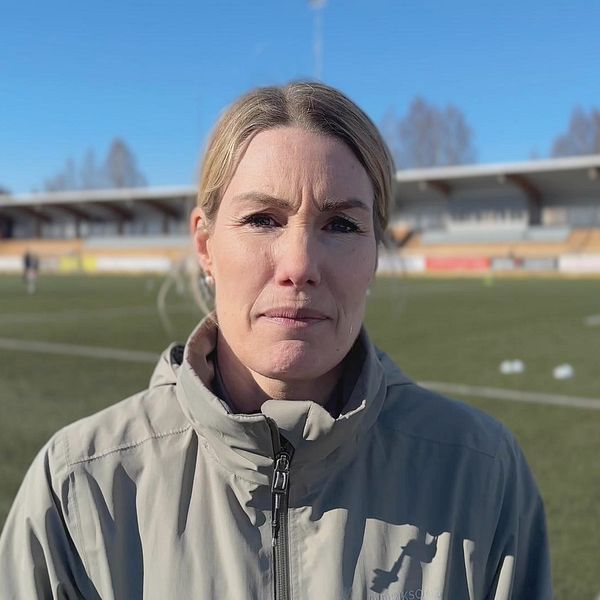 Fotbollsexperten Hanna Marklund står vid en fotbollsplan och tittar in i kameran