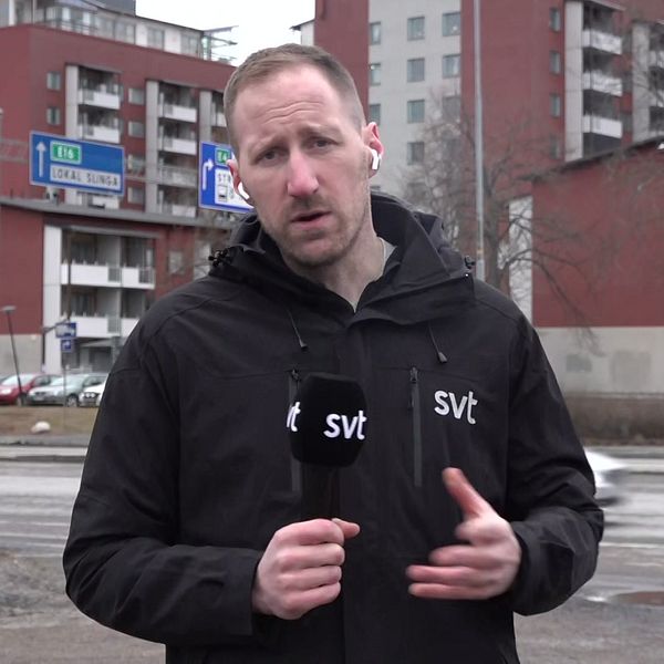 Reportern Arvid Jansson står framför flerfamiljshus och håller en SVT-mikrofon.